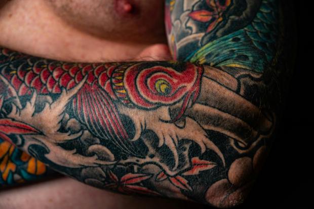 Close-up view of a colorful tattoo design on a person's forearm, featuring intricate patterns and images.