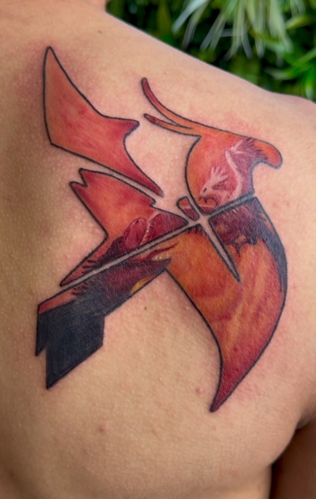 A full-color realism vibrant tattoo on the shoulder depicting an abstract design, featuring shades of orange and black.