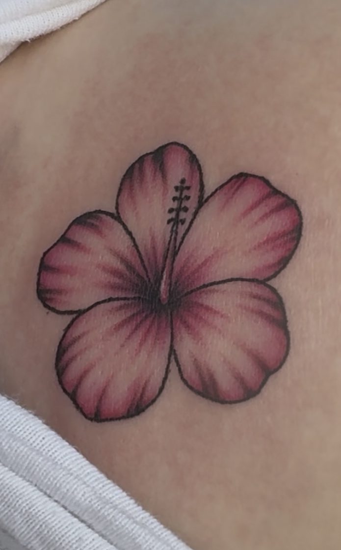 A close-up of a pink hibiscus tattoo on skin.